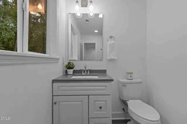 a bathroom with a granite countertop toilet sink and mirror