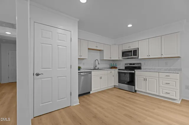 a kitchen with granite countertop white cabinets and stainless steel appliances