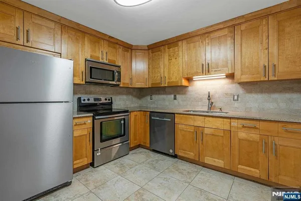 a kitchen with granite countertop cabinets stainless steel appliances and a sink