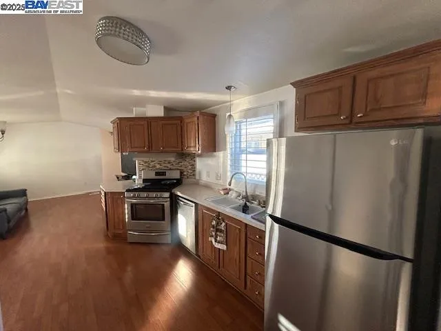 a kitchen with stainless steel appliances granite countertop a refrigerator a stove a sink dishwasher and a refrigerator with wooden floor