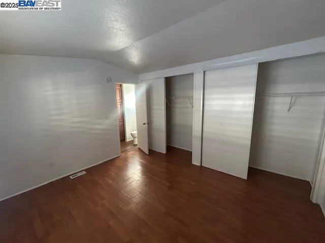 an empty room with wooden floor & closet area
