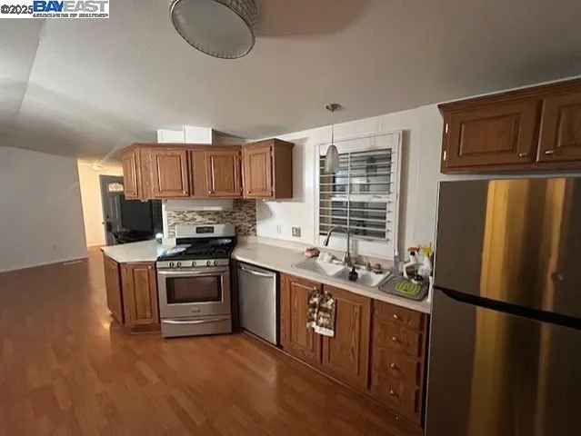a kitchen with stainless steel appliances granite countertop a stove a sink dishwasher a refrigerator and a microwave