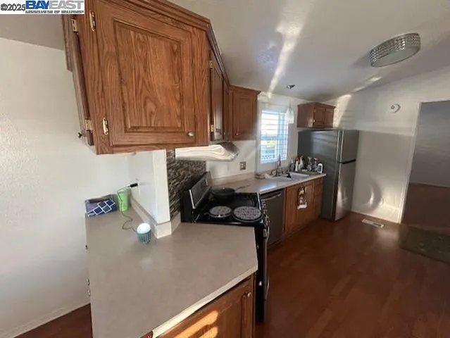 a kitchen with stainless steel appliances granite countertop a sink dishwasher stove and refrigerator with wooden floor