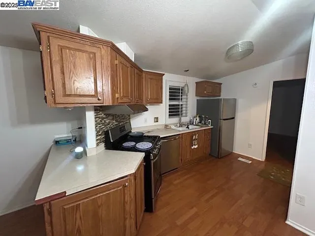 a kitchen with stainless steel appliances granite countertop a sink stove refrigerator and cabinets