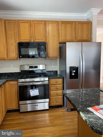 a kitchen with stainless steel appliances kitchen island granite countertop a stove a sink and a refrigerator