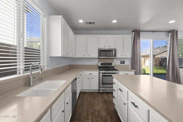 a kitchen with stainless steel appliances granite countertop a sink a stove and a refrigerator