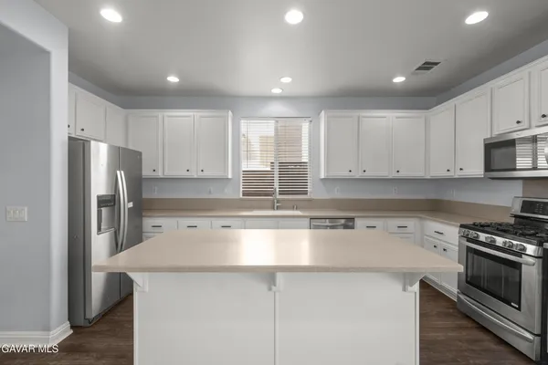a kitchen with kitchen island a counter top space stainless steel appliances and cabinets