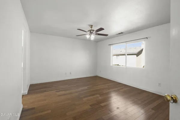 an empty room with windows and chandelier fan