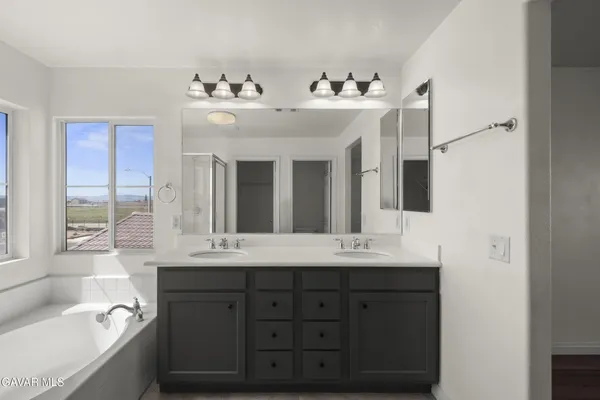 a bathroom with a double vanity sink mirror and bathtub