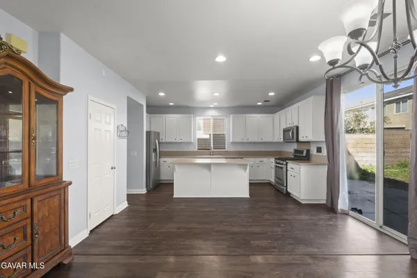 a large kitchen with a large counter top a sink stainless steel appliances and cabinets