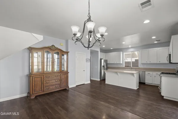 a kitchen with stainless steel appliances granite countertop a refrigerator a sink dishwasher a stove and white cabinets with wooden floor