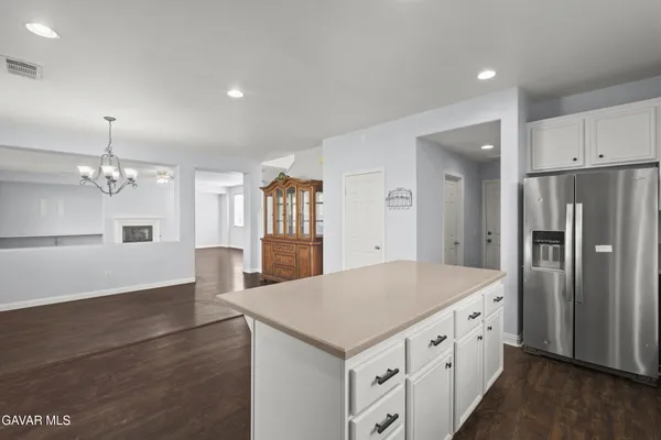 a kitchen with granite countertop a refrigerator a stove a sink dishwasher and white cabinets with wooden floor