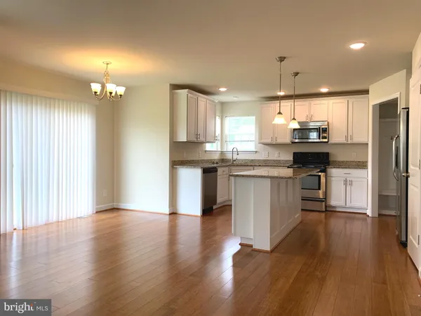 an open kitchen with wooden floor and stainless steel appliances