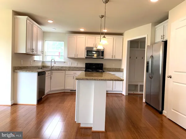 a kitchen with stainless steel appliances granite countertop a refrigerator a stove top oven a sink and wooden floor