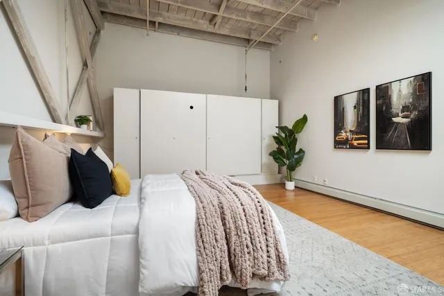 a bedroom with a bed and a potted plant on the dresser