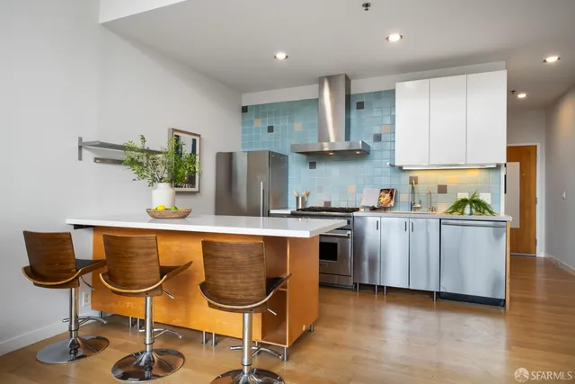 a kitchen with stainless steel appliances granite countertop a table chairs sink and cabinets