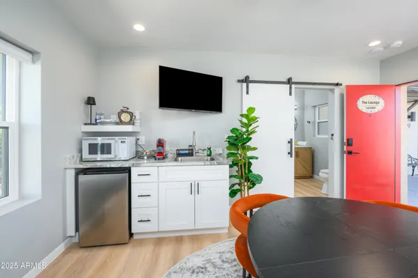 a living room with stainless steel appliances furniture and a flat screen tv