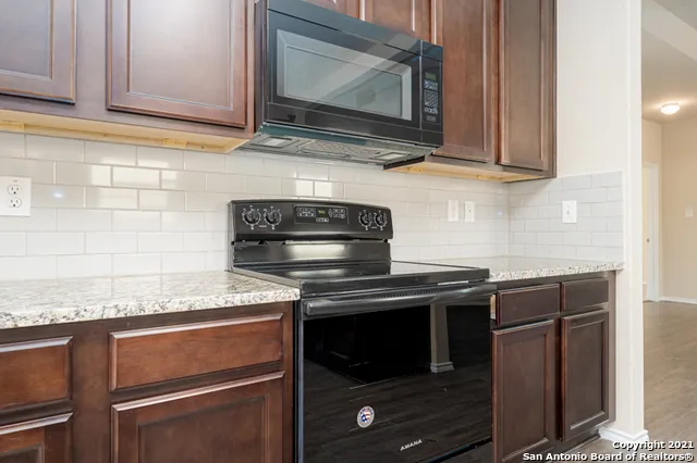 a kitchen with granite countertop cabinets stove and microwave
