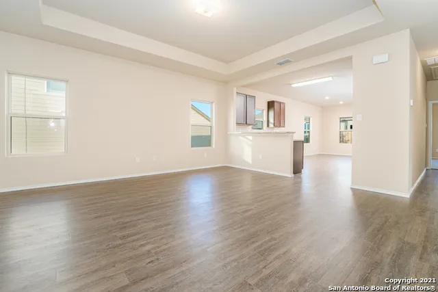 a view of a kitchen and an empty room with wooden floor and a window