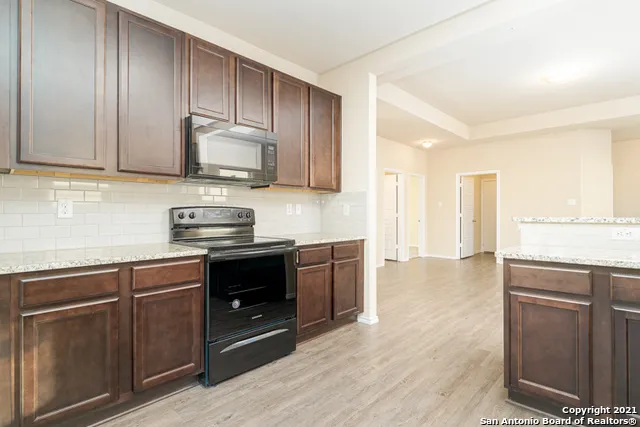 a kitchen with granite countertop wooden cabinets and a stove top oven