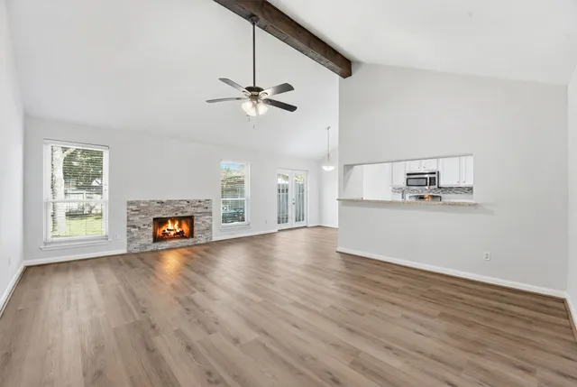 a view of an empty room with a window and wooden floor