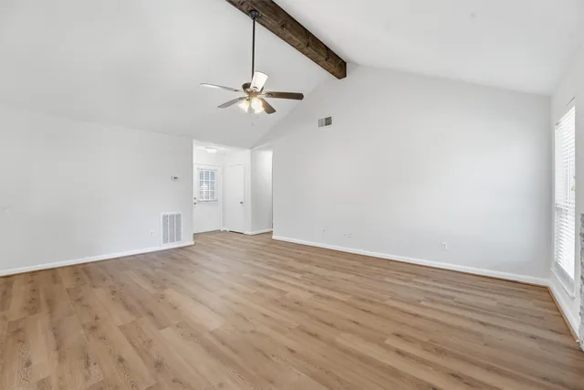 a view of empty room with wooden floor and ceiling fan