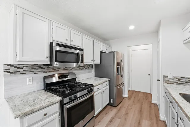 a kitchen with stainless steel appliances granite countertop a stove and a refrigerator