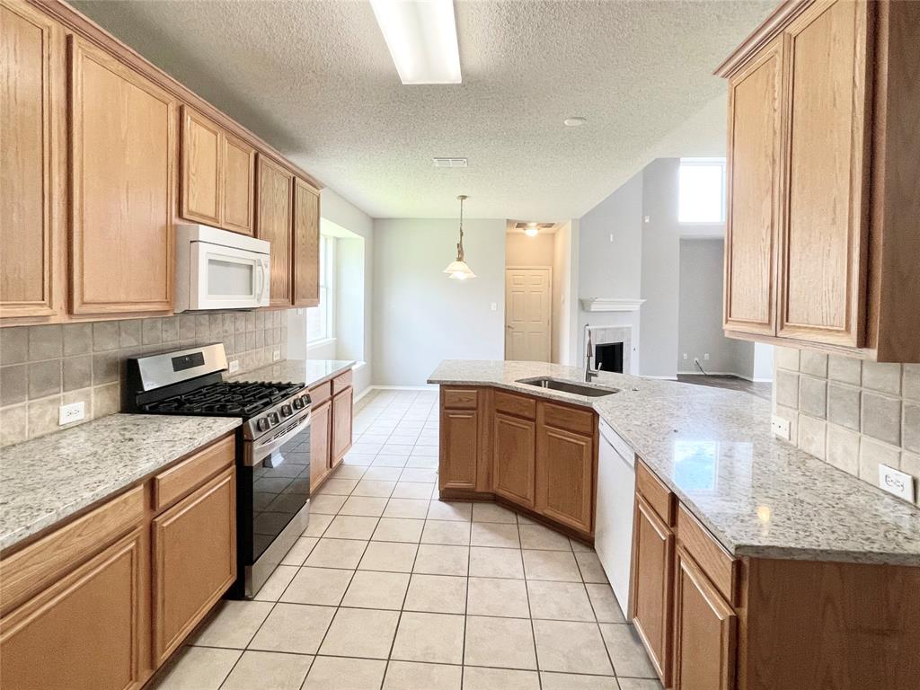7205 Prairie Flower Lane Frisco, TX 75033 - Photo 4 of 23 a kitchen with stainless steel appliances granite countertop a stove a sink and a microwave