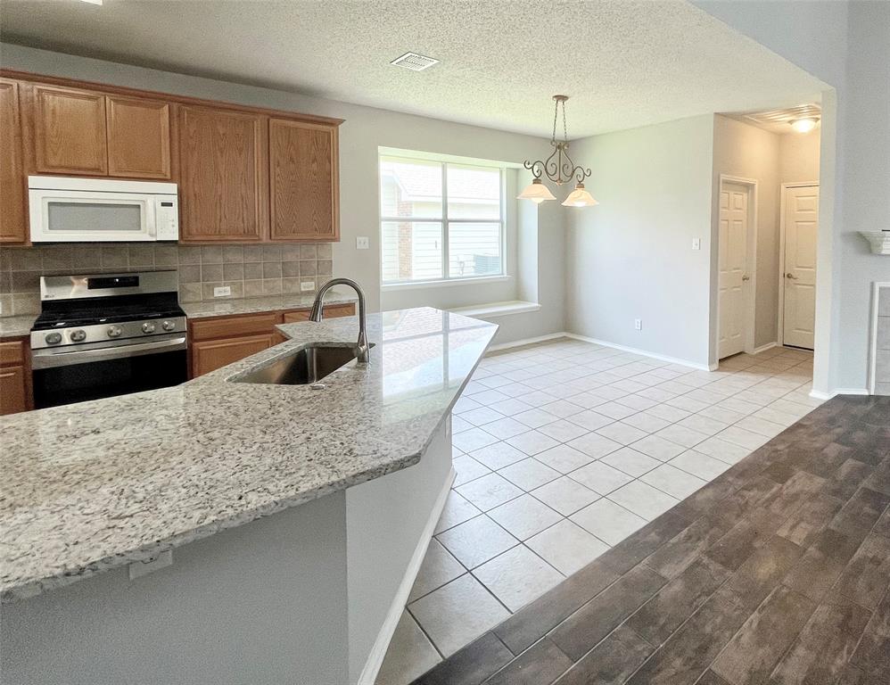 7205 Prairie Flower Lane Frisco, TX 75033 - Photo 7 of 23 a kitchen with stainless steel appliances granite countertop a sink stove and microwave