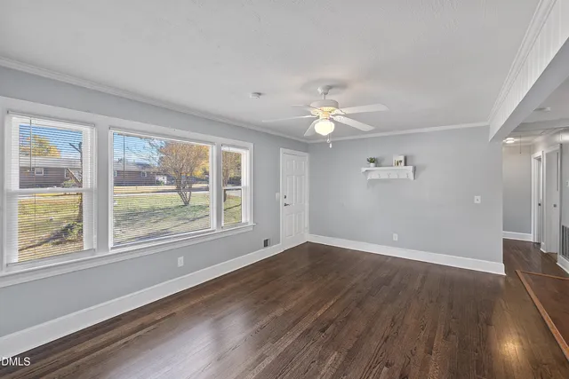 a view of an empty room with a window and wooden floor
