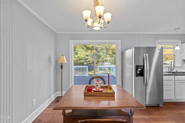 a view of a dining room with furniture a chandelier windows and wooden floor