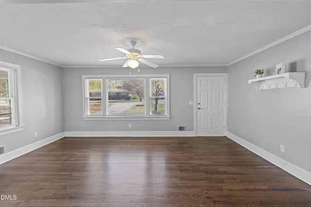 an empty room with wooden floor chandelier fan and windows