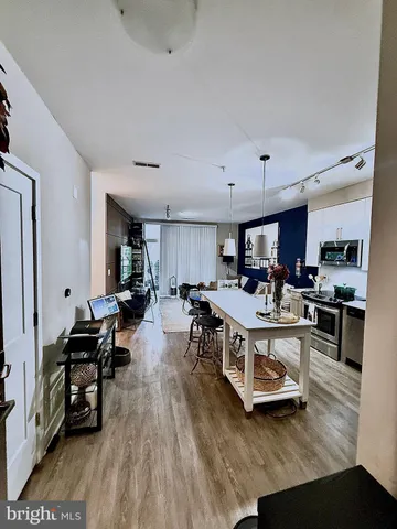 a open kitchen with stainless steel appliances granite countertop a stove refrigerator a dining table and chairs with wooden floor