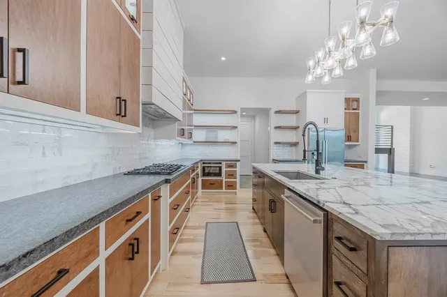 a kitchen with stainless steel appliances granite countertop a kitchen island a stove and a sink