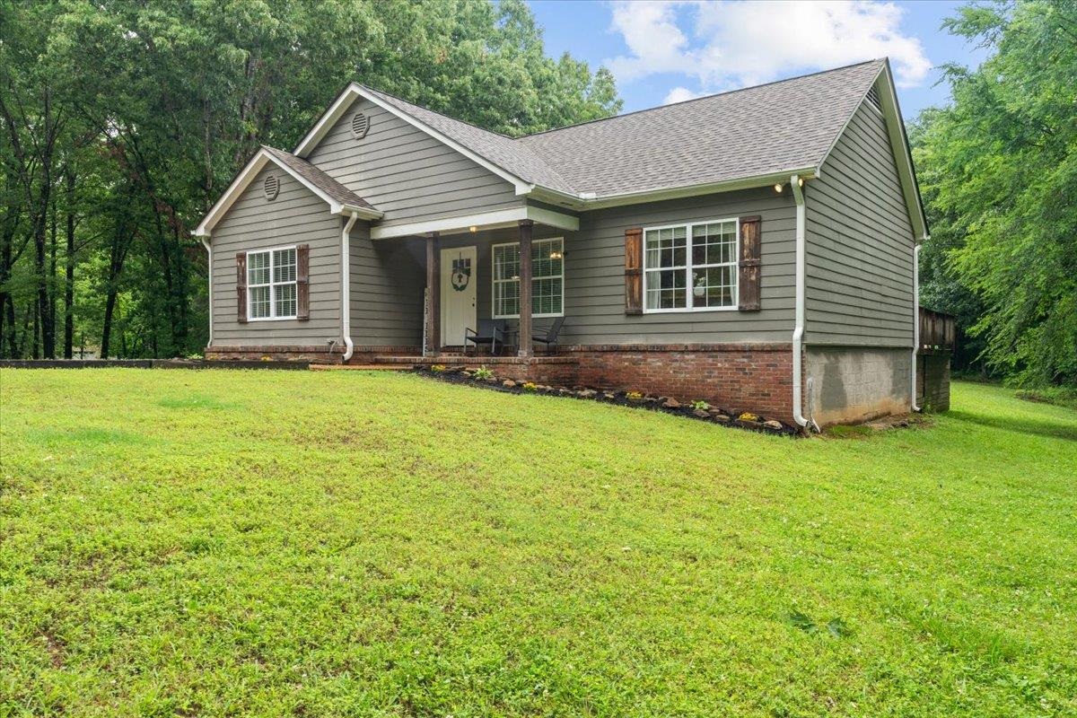 150 Liberty Road Moscow, TN 38057 - Photo 2 of 36 Contemporary residential exterior featuring a covered front porch with dark wood columns, gray siding, a brick foundation, and a dark shingle roof