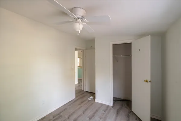an empty room with wooden floor closet and windows