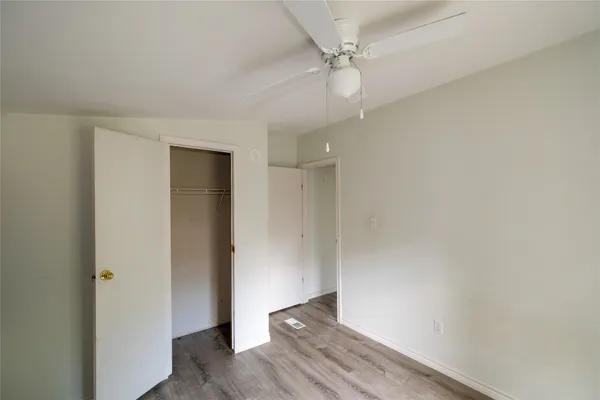 an empty room with closet and a ceiling fan
