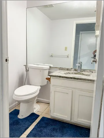a bathroom with a granite countertop toilet sink and mirror