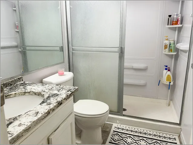 a bathroom with a granite countertop sink toilet and shower