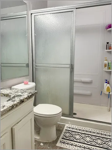 a bathroom with a granite countertop toilet and a shower