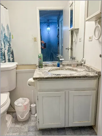 a bathroom with a granite countertop sink a toilet and a mirror