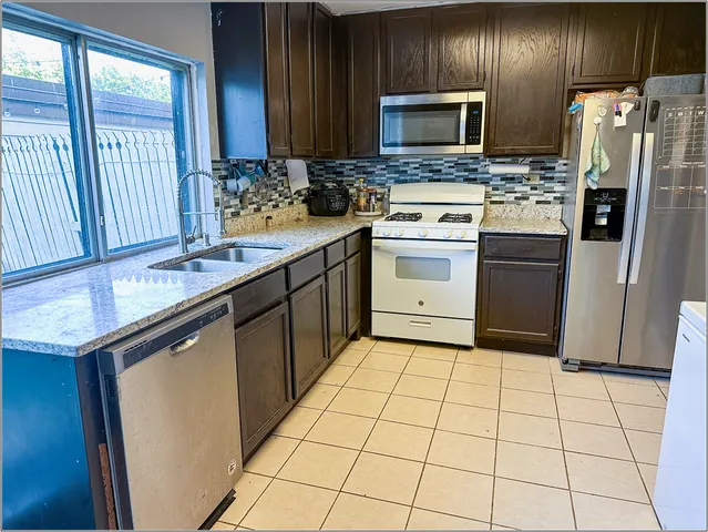 a kitchen with stainless steel appliances granite countertop a stove a sink and a refrigerator