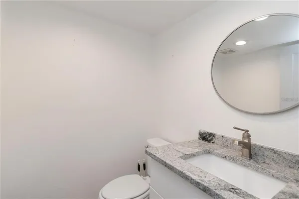 a bathroom with a granite countertop toilet sink and mirror