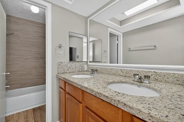 a bathroom with a granite countertop sink and a bathtub