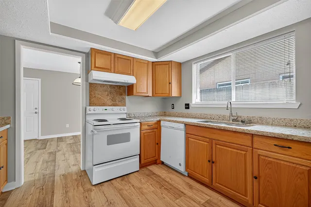 a kitchen with granite countertop a sink cabinets stainless steel appliances and a window