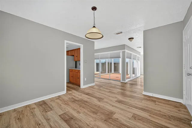 a view of an empty room with wooden floor and fan