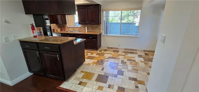 an empty room with wooden floor fireplace and windows