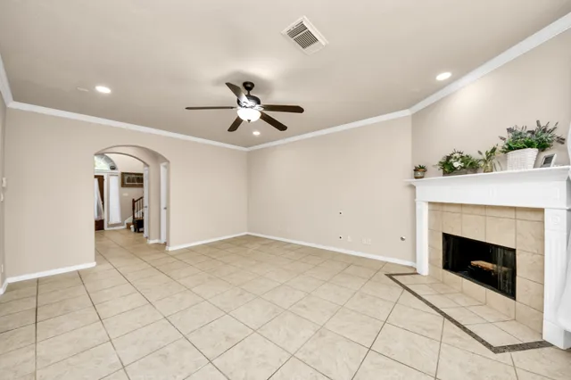 a view of an empty room with chandelier fan and fire place
