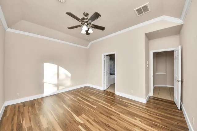 a view of empty room with wooden floor and fan