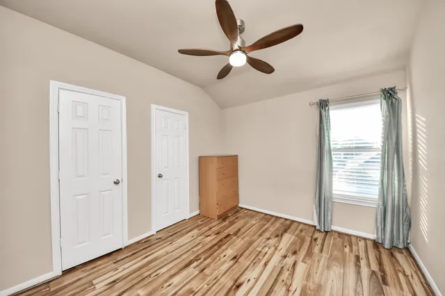 a view of empty room with wooden floor and fan